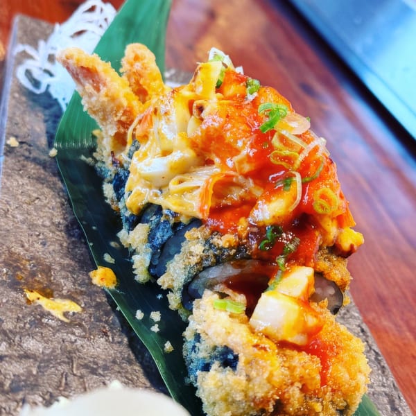 Kami Sushi's deep-fried sushi roll topped with shrimp tempura, spicy sauce, and scallions.